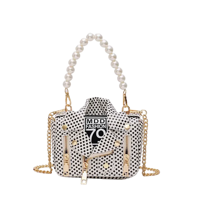 Polka dot handbag with gold chain and pearl handle on a white background