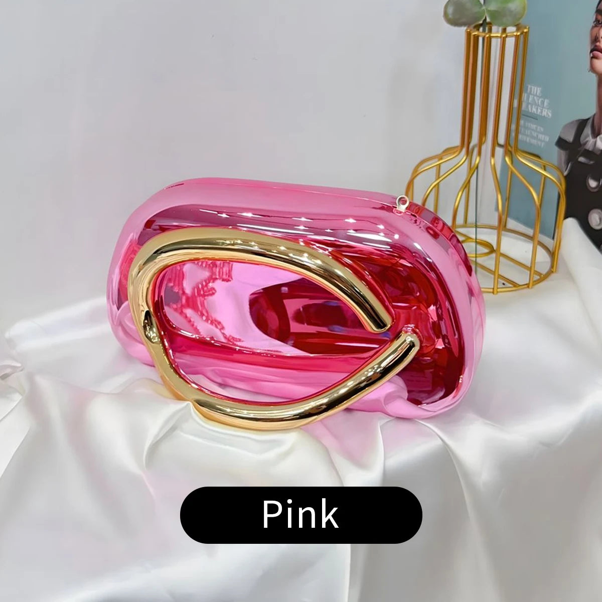 Pink Carauana Festival Clutch Bag with gold accents on a white surface