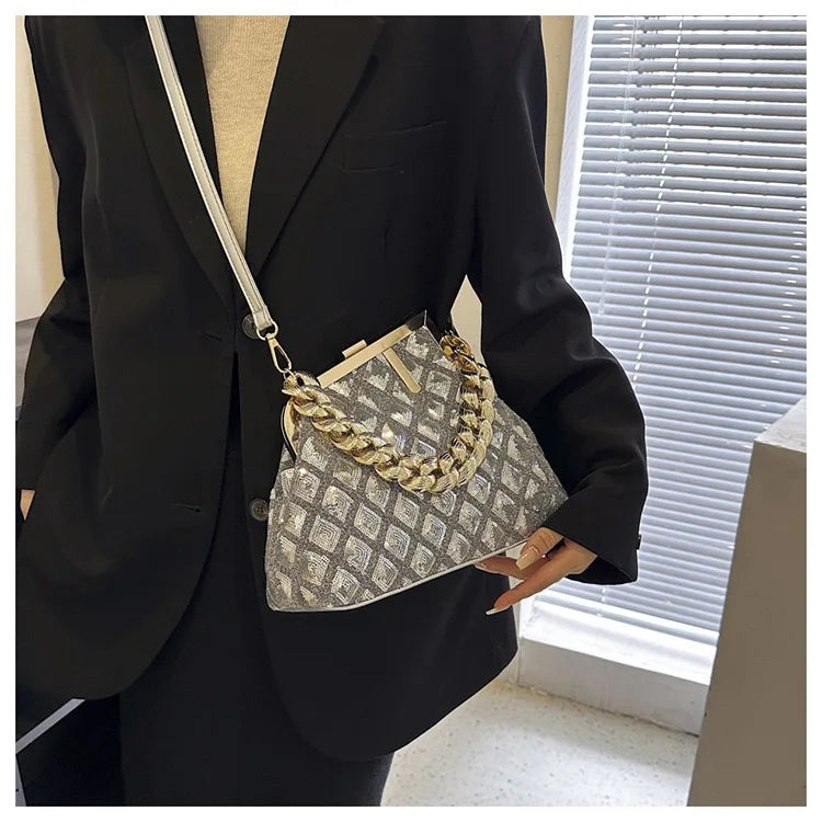 Person wearing a black blazer holding a patterned handbag with gold chain detail.