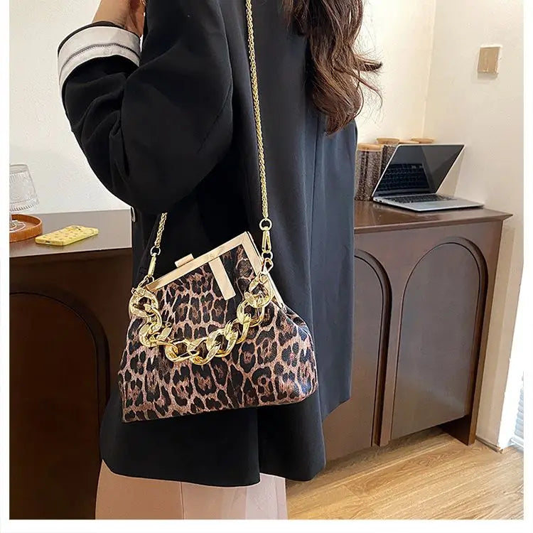girl holding a Carauana_UNIU_Leopard_Clutch with gold chain detail in an indoor setting.