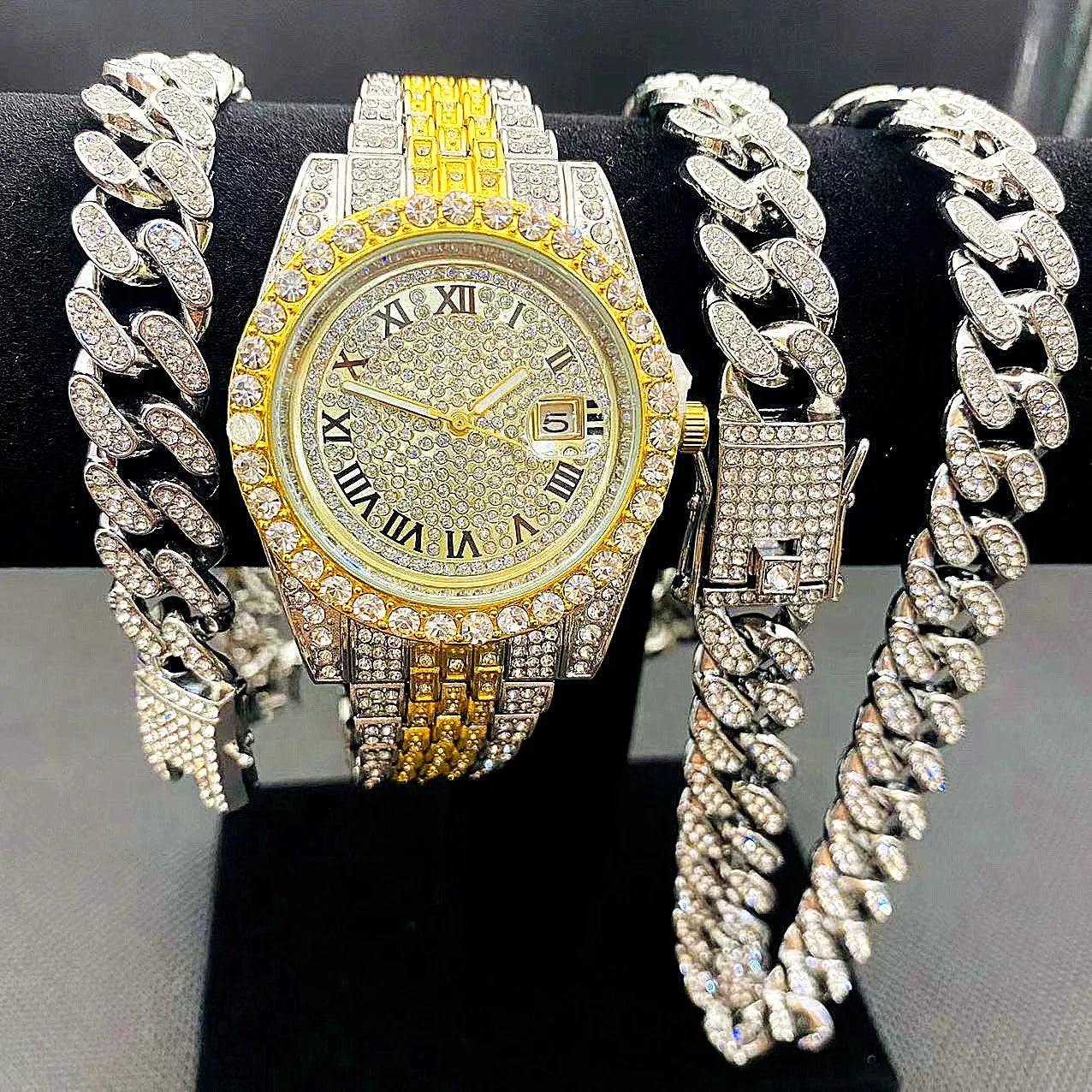 Gold watch with diamond-studded band and silver chain bracelet on black background