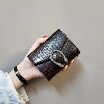 Hand holding a coffee Carauana compact wallet crocodile patterned wallet with a gold buckle